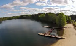 Widok jeziora z pomostem. W tle plaża