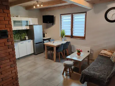 Zdjęcie kuchni, w tle sofa, krzesła lodówka, szafki