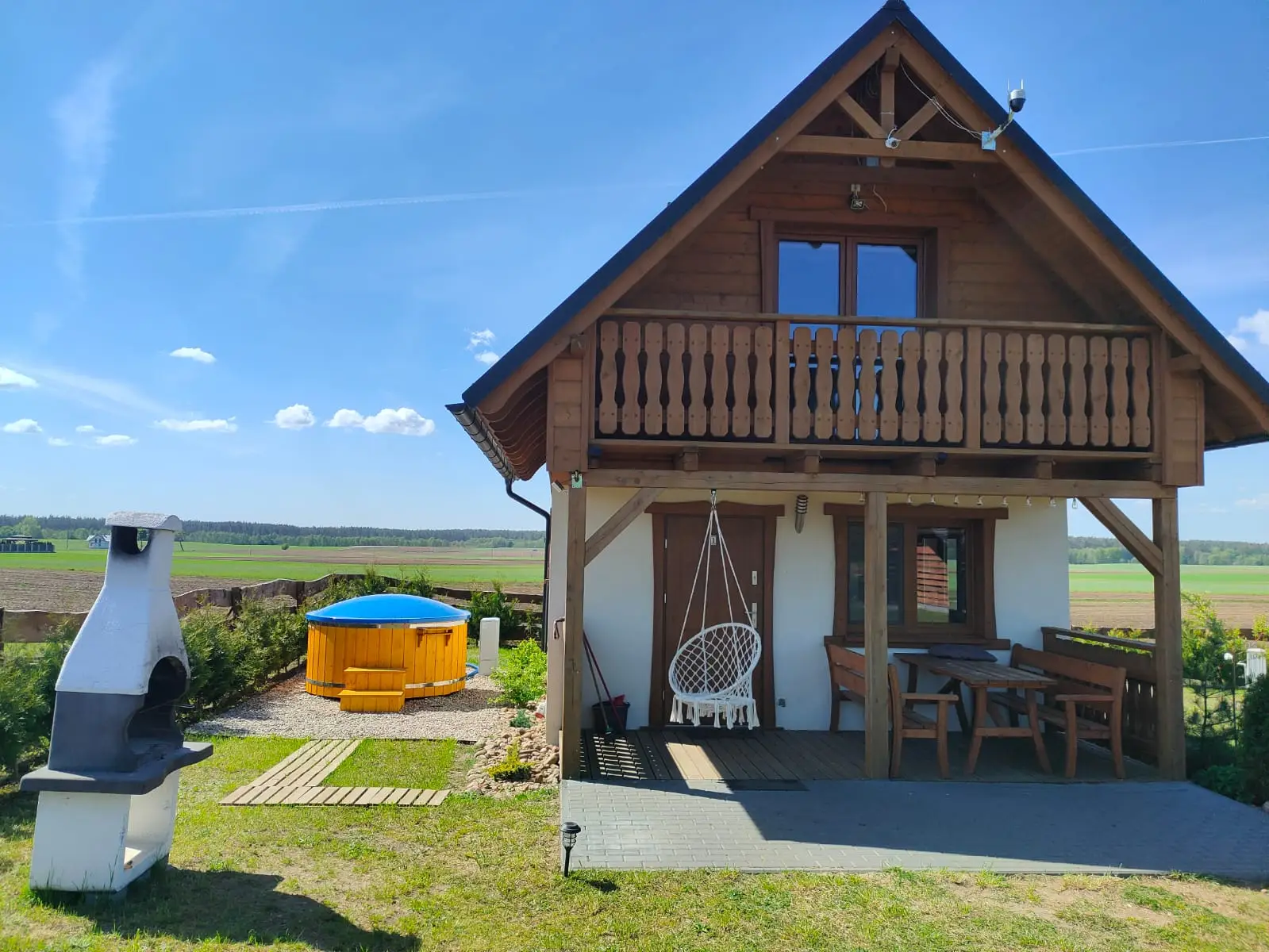 Domek Iga znajdujący się w prawej części zdjęcia. W tle widoczne huśtawki oraz grill