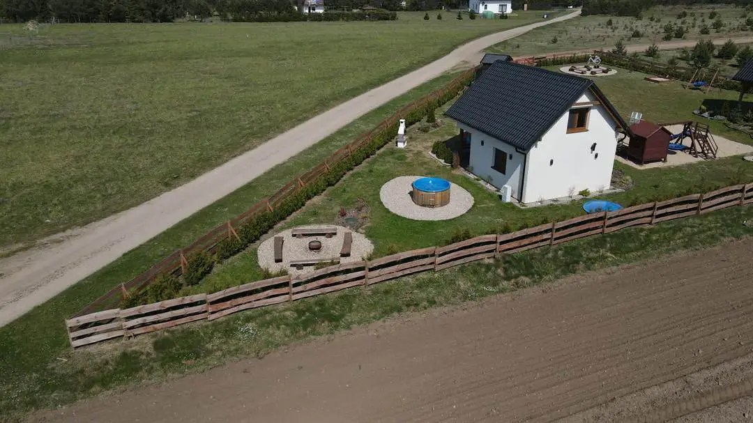 Zdjęcie domka z oddali. W tle widoczna bramka do piłki nożnej.