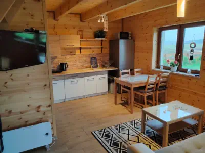 Zdjęcie kuchni, w tle sofa, krzesła lodówka, szafki